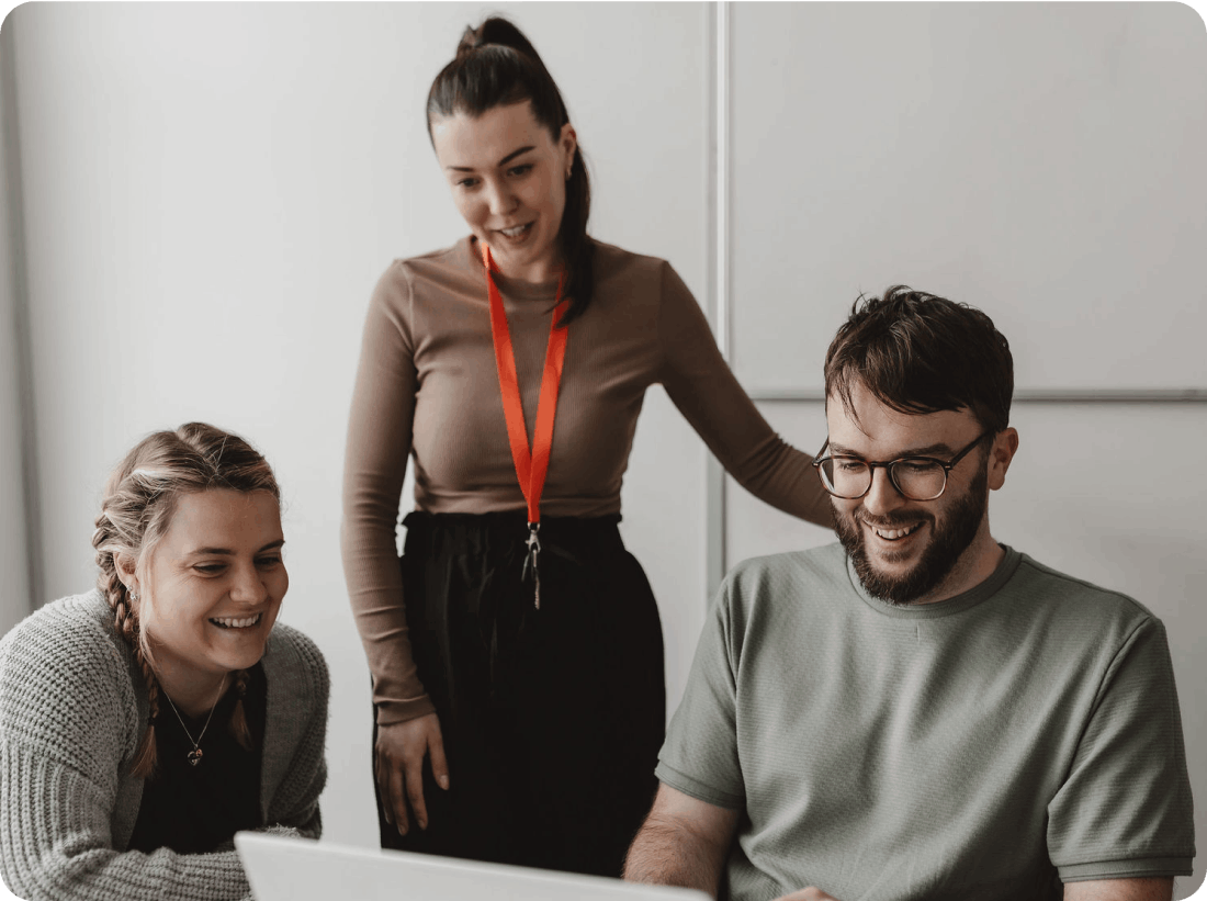 3 Onecom employees looking at a laptop sat down and standing