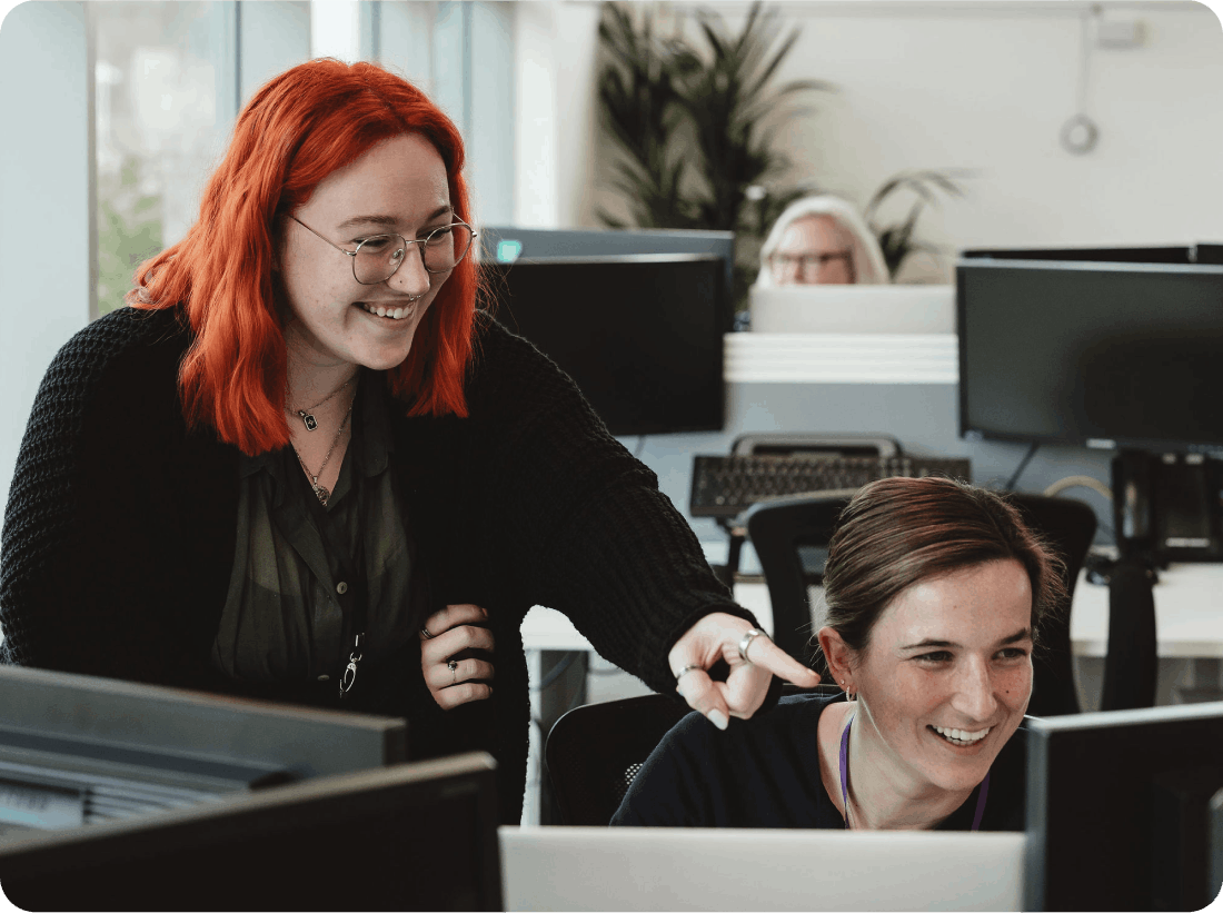 Two female Onecom employees looking at computer screen