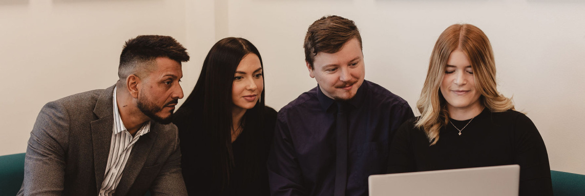 4 Onecom employees looking at laptop sat on sofa